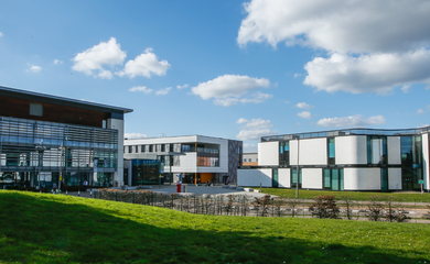 Modern buildings at University of Hertfordshire campus in the sunshine, with students walking to their classes.