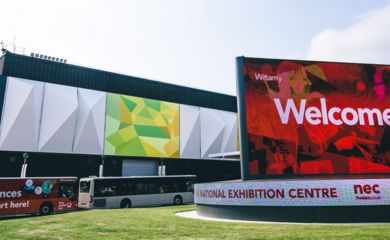 The entrance to the Piazza shows a large electric board reading 'Welcome.'