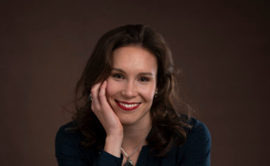 A headshot photo of Beth Wooller, a white woman with brown hair, smiling at the camera