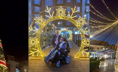 Two people – Emma Purcell and her mum Carol - are enjoying a festive outdoor light display in the evening at Gunwharf Quays in Portsmouth. Emma sits in a powered wheelchair with a blanket over her lap, smiling toward the camera, while Carol stands behind Emma, also smiling. They are positioned beneath a large illuminated arch decorated with glowing golden snowflake designs. Snow-dusted Christmas trees line the walkway, and buildings with shopfronts and balconies are visible in the background.