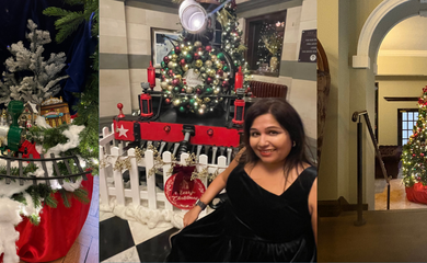 Tanvi smiling at camera with a christmas tree in the background and a toy train with fake snow