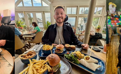 Ross at a dinner table in a restaurant smiling to camera with plates of food on the table in the foreground