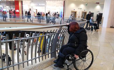 Woman in wheelchair browsing rails of clothes in a shop