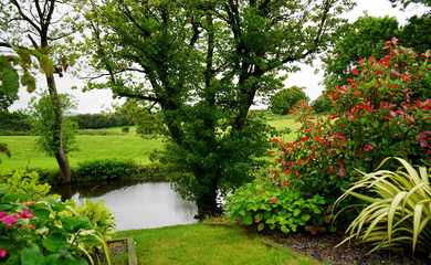 Pretty gardens with lots of green grass, flowers and trees with a stream running through