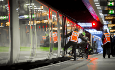 A wheelchair user being assisted on to a train using a ramp