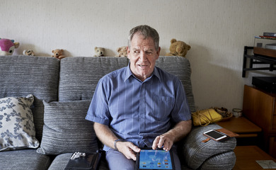 Visually impaired man using apps on a tablet device at home 
