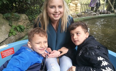 Image of Natalie, a white women with blonde hair sitting in a boat with her two sons.