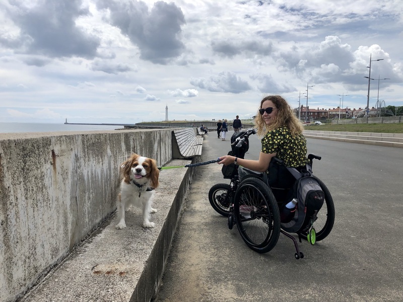 Carrie-Ann Lightley, a female wheelchair user, walking her dog along the promenade by the sea.