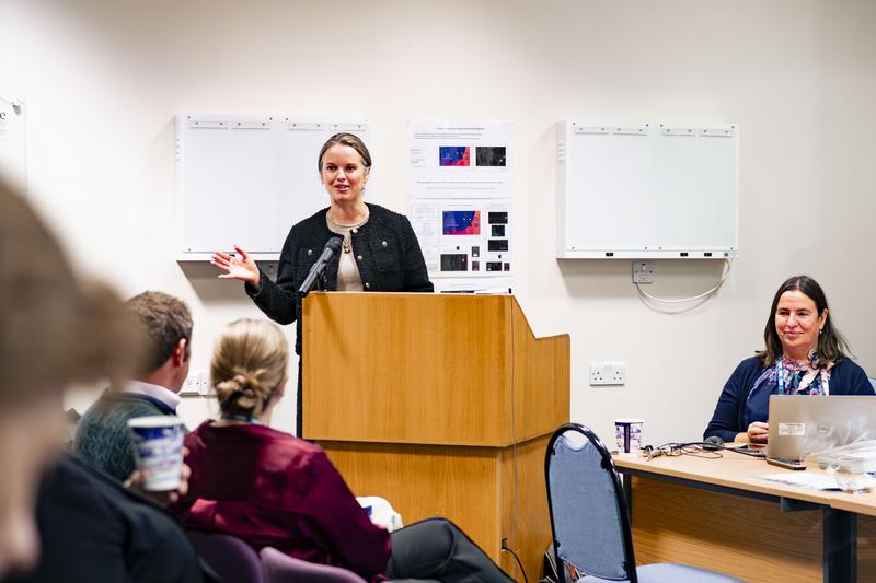 Anna Nelson speaking in a conference room to a row of seated people 
