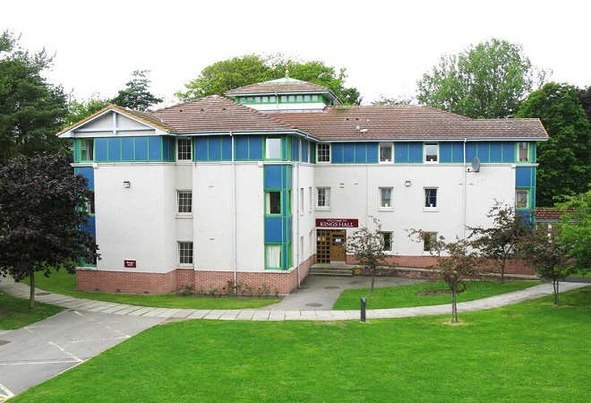 "External image of Halls of Residence building with a blue and white exterior and grass in forefront"