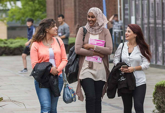 Three female students walking outside, chatting