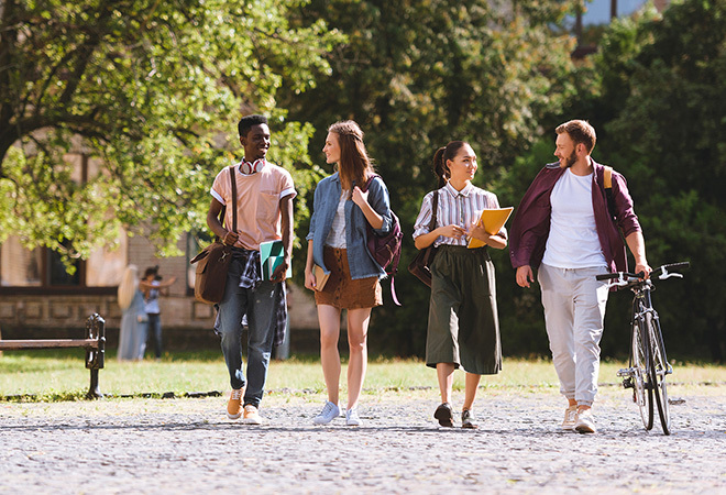 Four students walking towards the camera, facing each other and talking