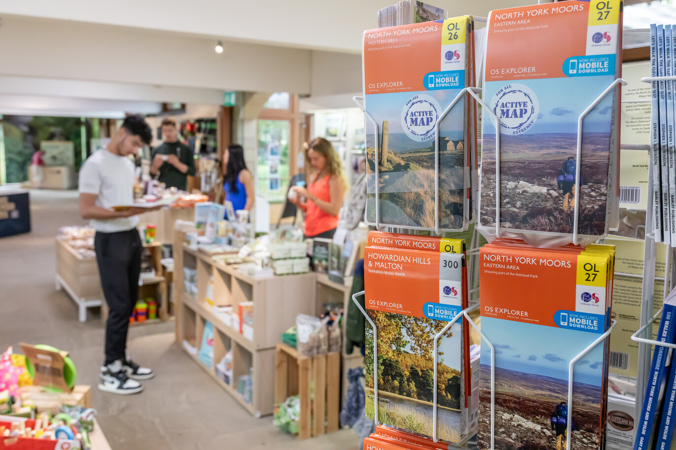 "Gift Shop at Sutton Bank with a close up of the North York Moors maps available to buy, multiple people browsing in the background"