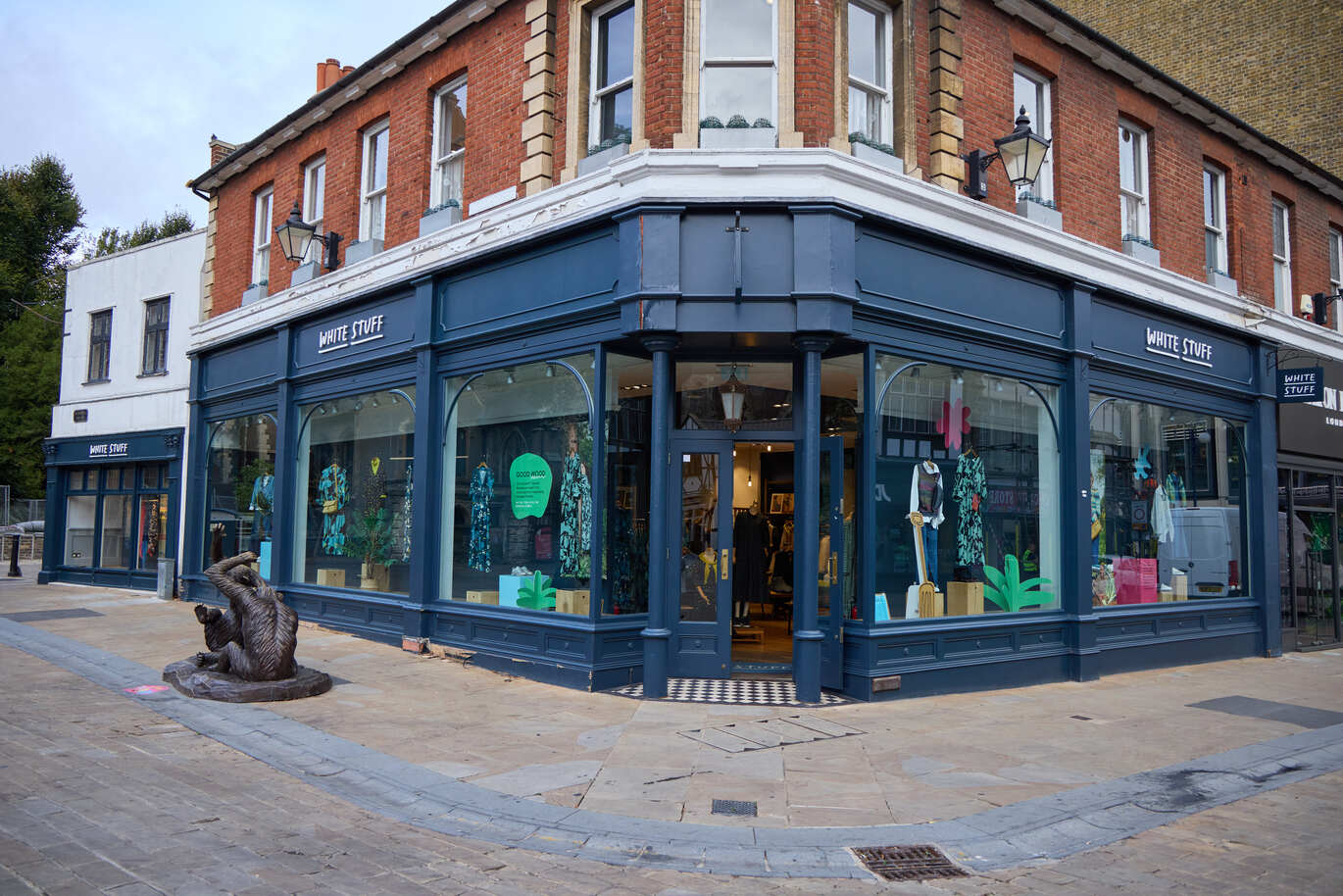 Outside view of a large store painted dark blue with an iron statue of some monkeys out the front on the pavement.