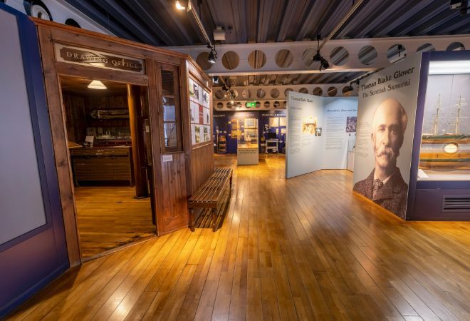 "Exhibition at Maritime Museum. Wooden floors and bench. Picture of man which reads Thomas Blake Glover, The Scottish Samurai."