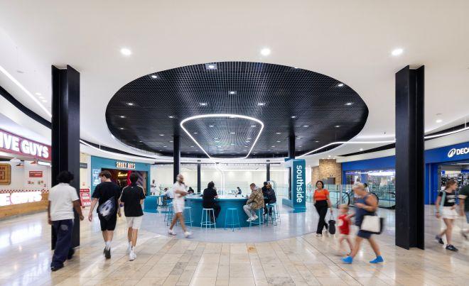 "Central kiosk seating area at Southside with circular ceiling feature and people walking around."