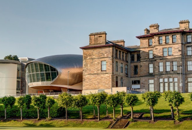 "University buildings, one traditional in style and one modern silver building set against blue skies"