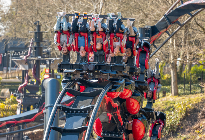 "Inverted rollercoaster with riders hanging upside down as the train curves along the track."