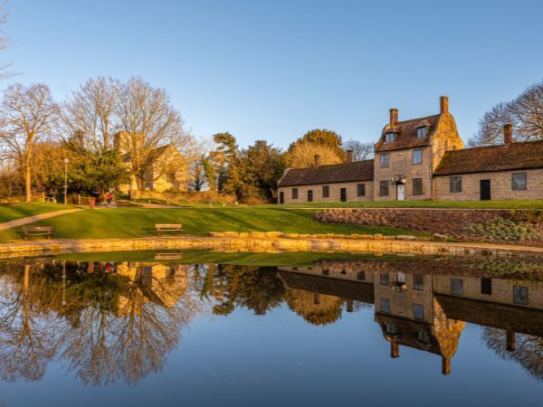"A still area of water against the backdrop of of a church and stone buildings"
