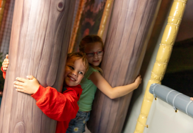 two children hugging tree trunks