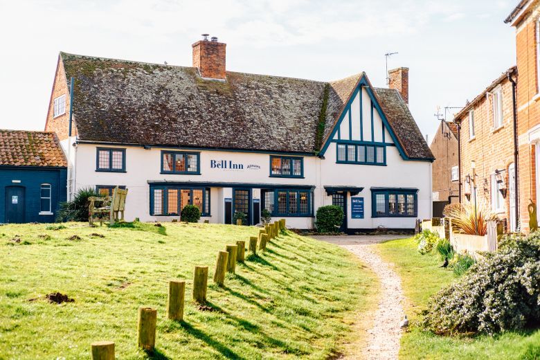 "External view of The Bell Inn - a tudor style building with a path leading up to it next to a green patch of grass"
