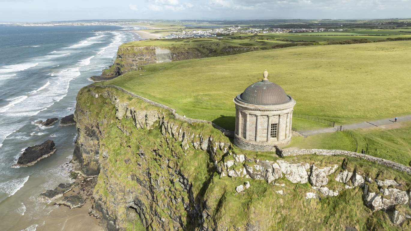 Aerial view of the 18th century Mussenden Temple at Downhill Demesne on a cliff top with the beach and sea below.