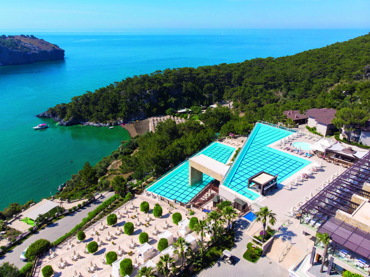 View of the hotel complex surrounded by a forest of trees with infinity pools looking out over the sea.