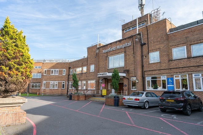 Photo of entrance to Harefield Hospital. There are accessible parking bays to the right. There is a stepped entrance directly in front of the entrance doors.