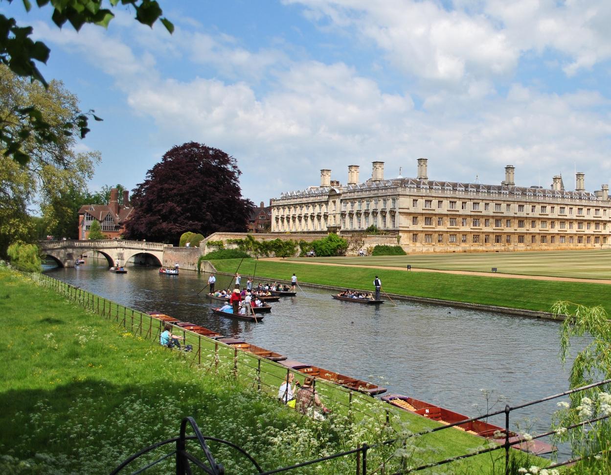 "Clare College building in background, river in the foreground with people in punting boat"