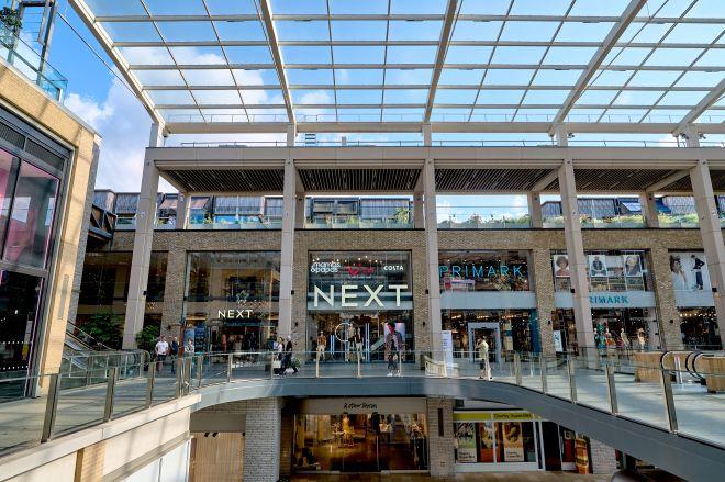 "Westgate shopping centre with upper-level walkway, glass canopy and shops including Next and Primark."