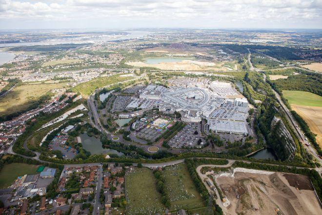 "Aerial view of Bluewater shopping centre with surrounding car parks, roads and green landscape."