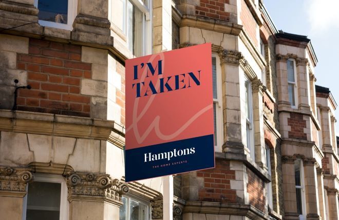 "Photo taken in front of brick town houses. A sign is in view that says "I'm Taken Hamptons The Home Experts"