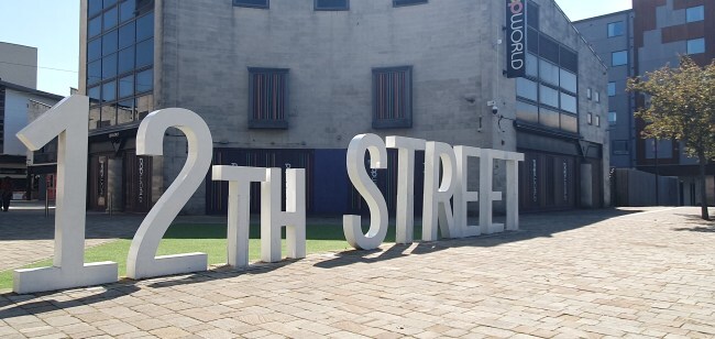 12th street sign in sunshine, building in background bather in sun