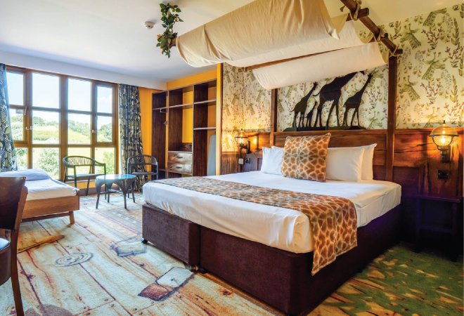 "interior of the Chessington World of Adventures hotel, with a bed, and a view of the safari"