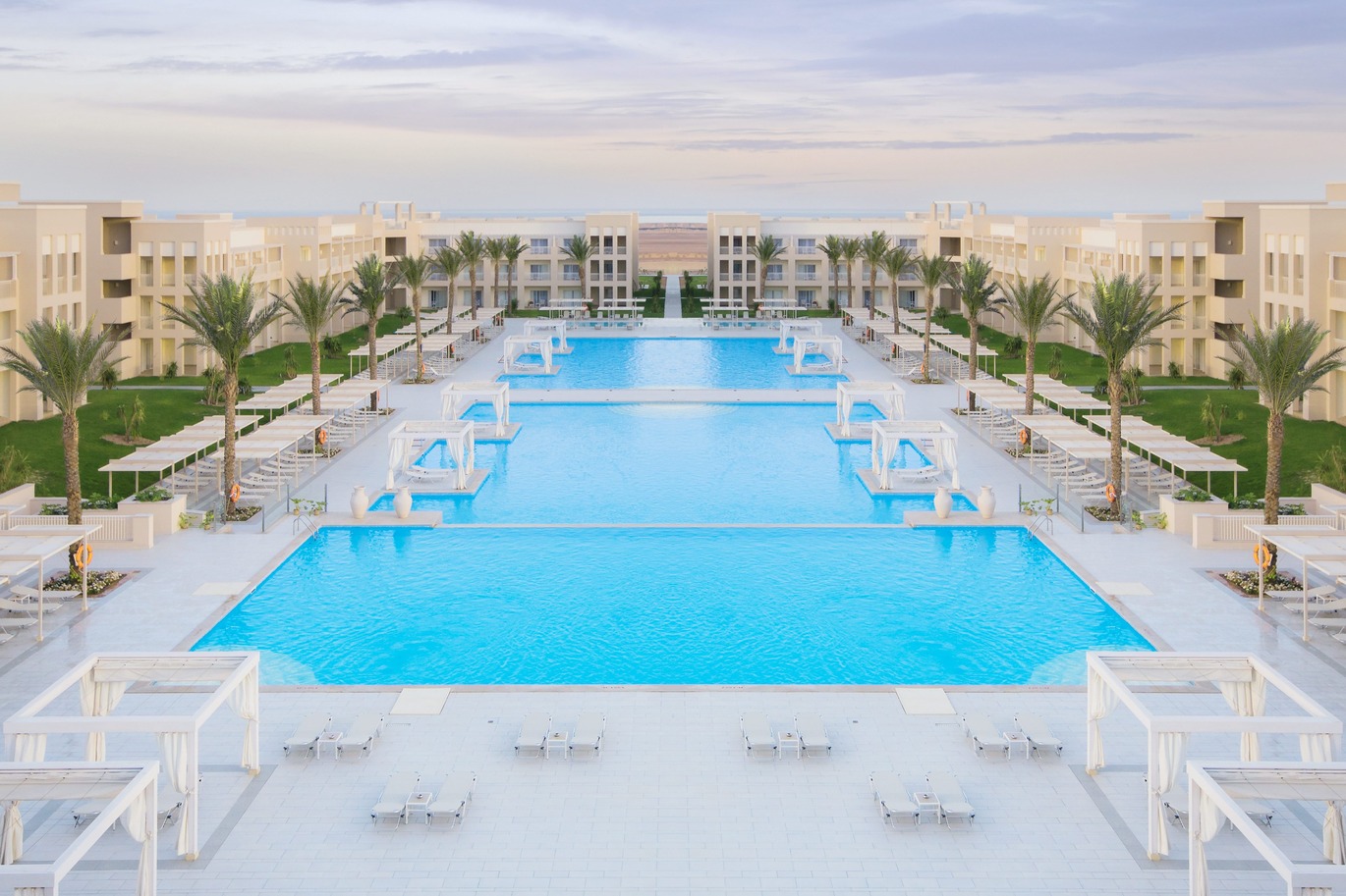 View of the pool area surrounded by the hotel buildings, with sun loungers around the pool.