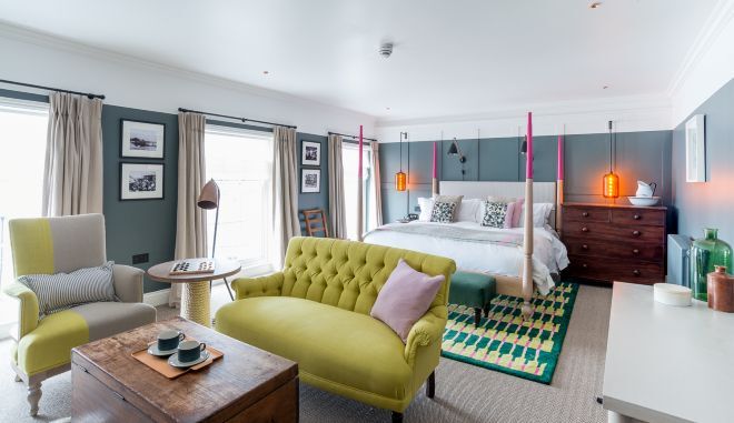 "Modern light and grey bedroom with double bed and green sofa chair at Swan Hotel"