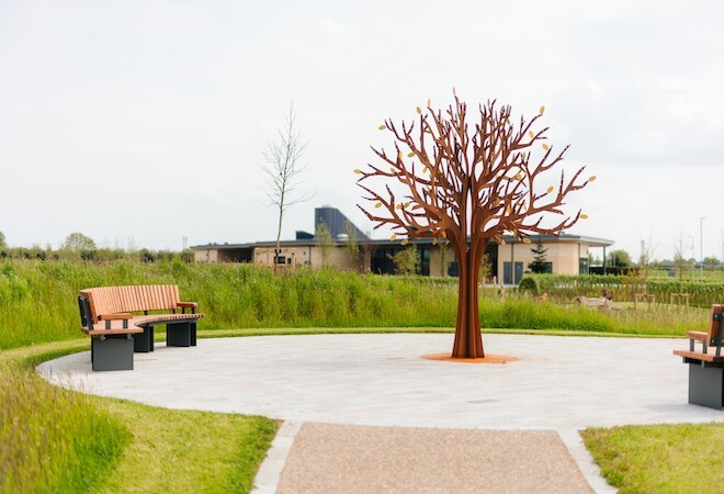 "Image depicts an outside scene with seating and the bronze coloured memorial tree"