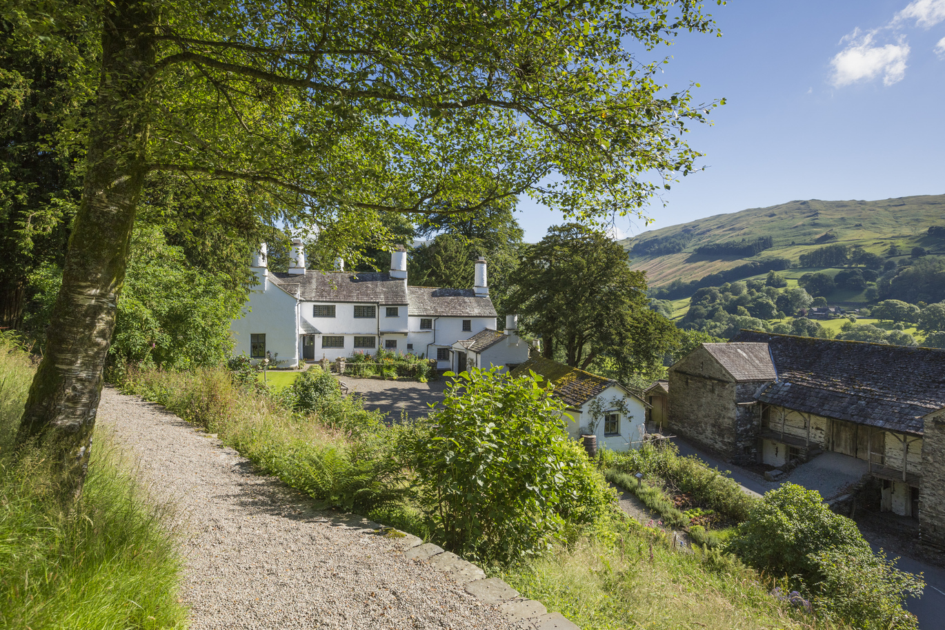 Exterior view of the 17th century Townend surrounded by woodland with beautiful scenery behind.