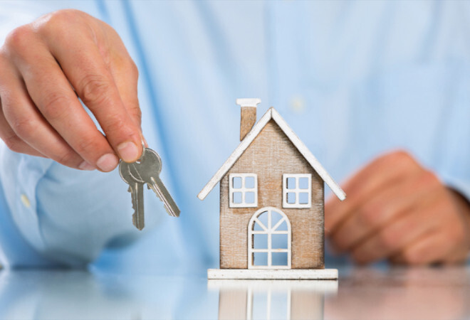 A small house figure with someone holding keys next to it