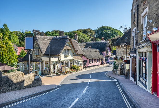 "A colourful village street with buildings with thatched roofs"