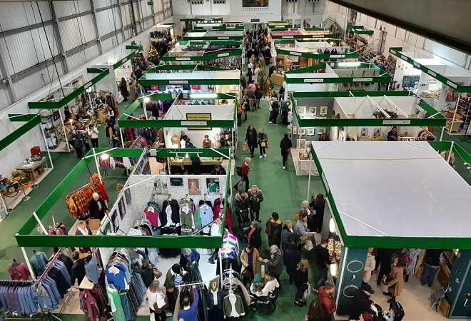 "A photograph showing a bustling, long, rectangular exhibition space set up with a variety of different retailers"
