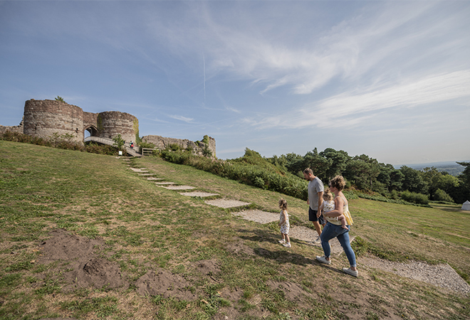 "A male and femme adult walking up stepping stones to the top of a hill, accompanied by a small child"