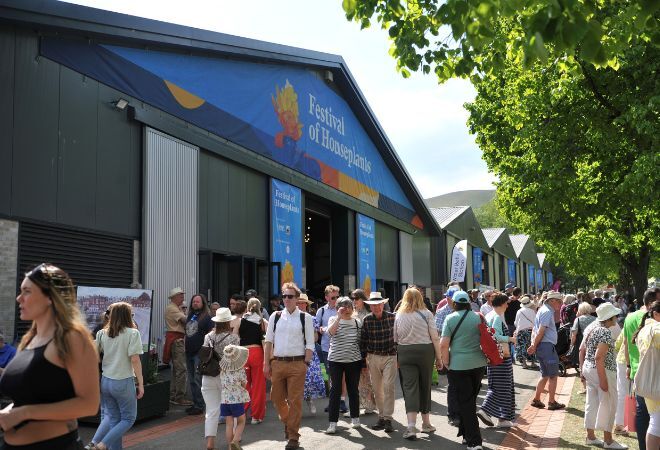 "One of the buildings with 'Festival of Houseplants' on the facade and a crowd of people walking by"
