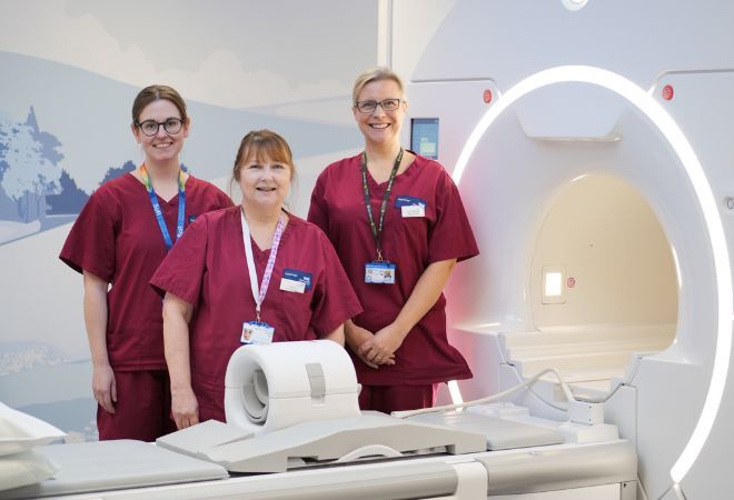 "West Suffolk Hospital staff standing next to an MRI machine"