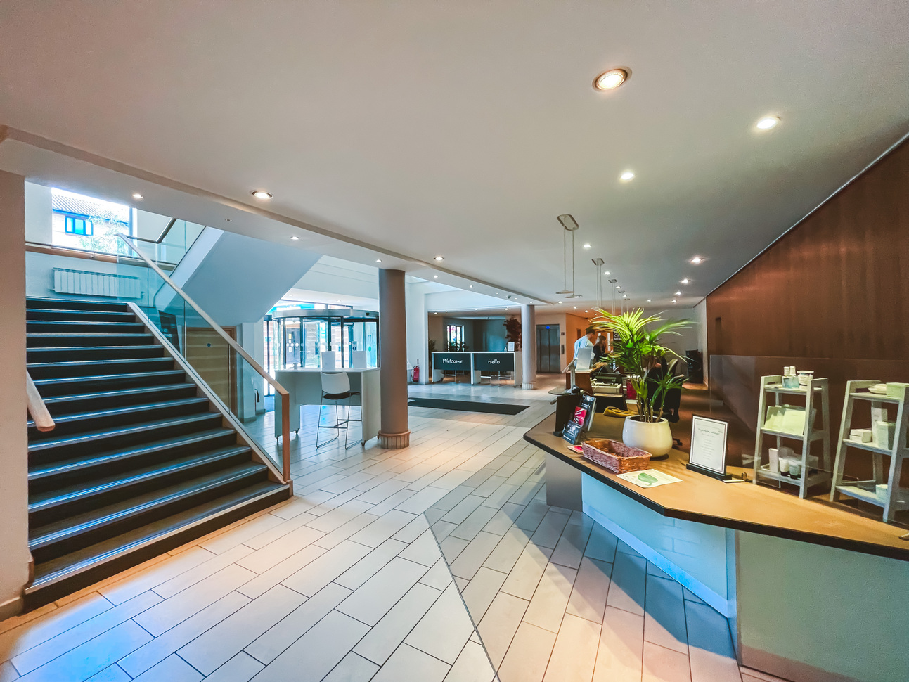 "Reception area with staircase on the left and reception desk on the right, tiled floor with columns near staircase"