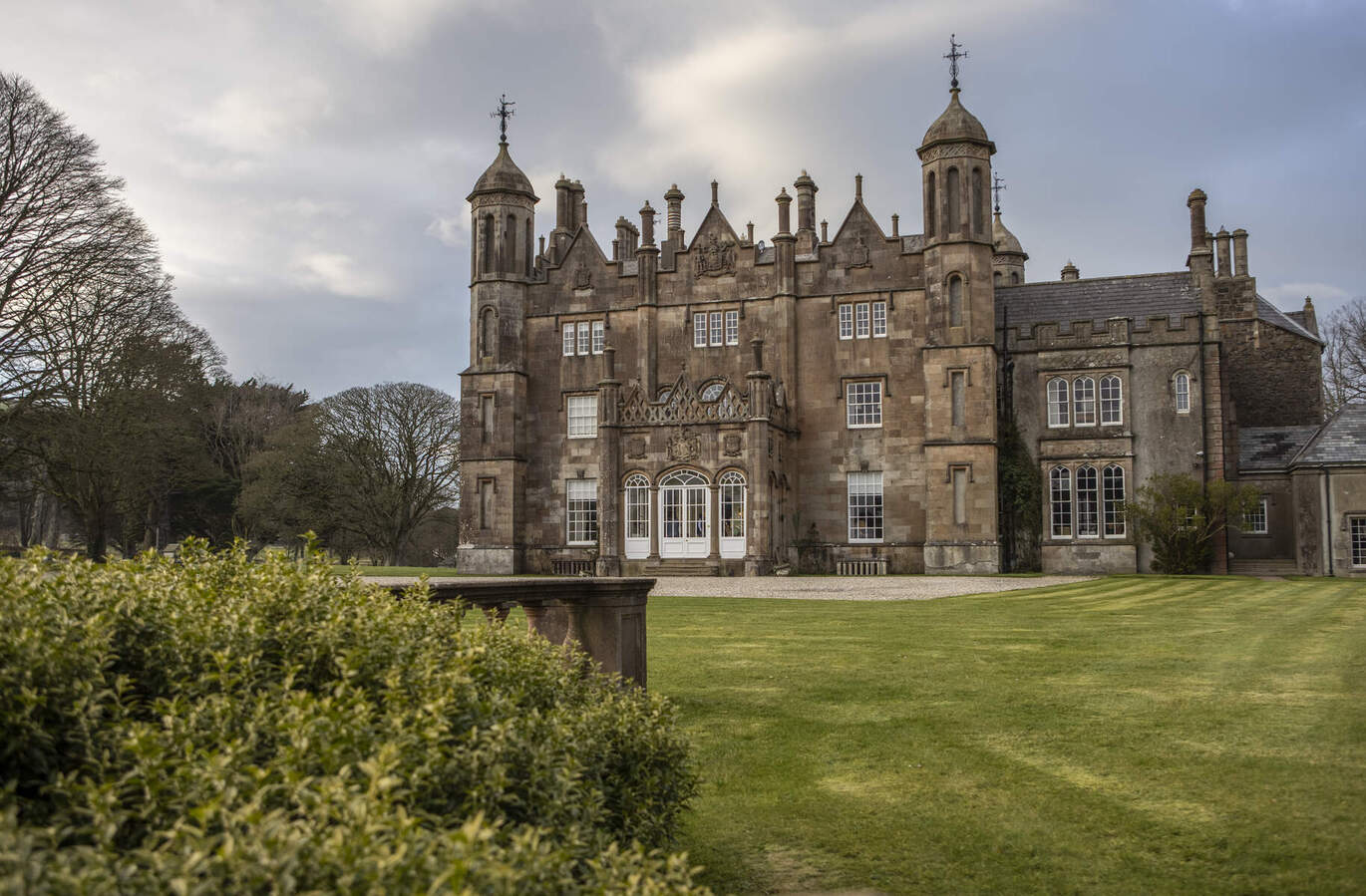 "Glenarm Castle against a blue sky with a grassy area in front"