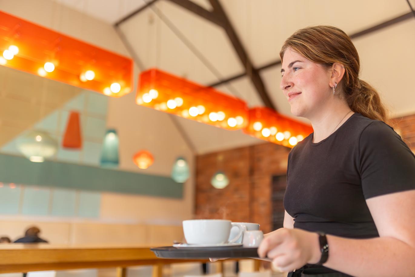 "Welbeck Estate internal shot of a femme presenting person serving a coffee inside the Harley Cafe"