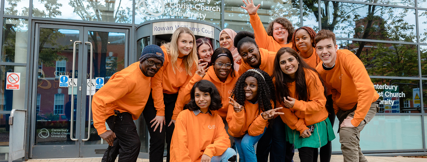"Image of students all wearing bright orange CCCU hoodies outside of Rowan Williams Court at Medway Campus"