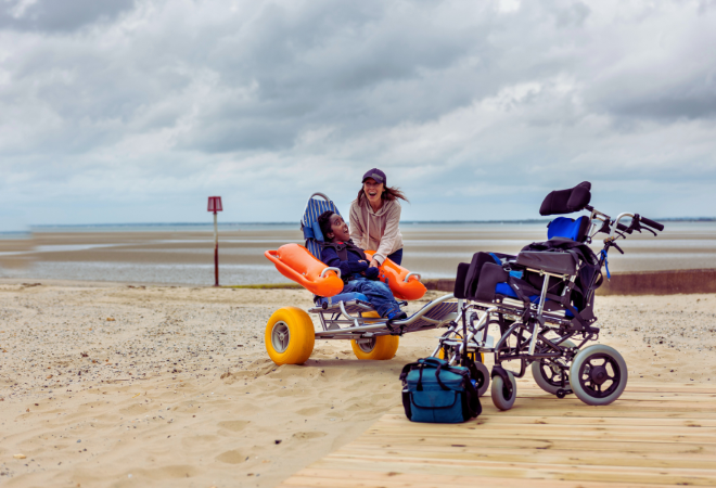 "A beach-goer enjoying a day on the beach using a sand use wheelchair"