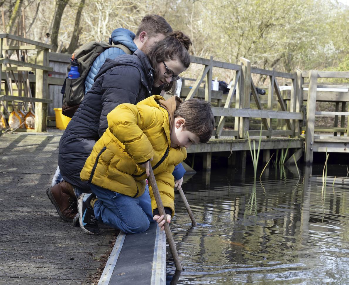 "young child with stick in water"